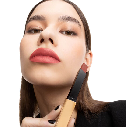 Mano sosteniendo un tubo cerrado de labial YSL negro y dorado.