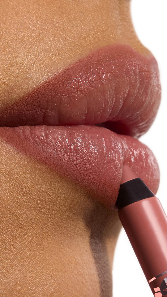 Primer plano vertical de unos labios mate marrón rosado con la aplicación de un perfilador a juego.