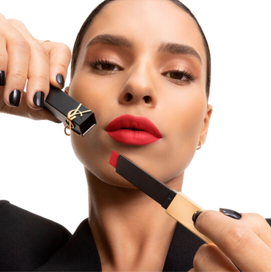 Mano mostrando un labial YSL cuadrado rosa suave junto a la mejilla.