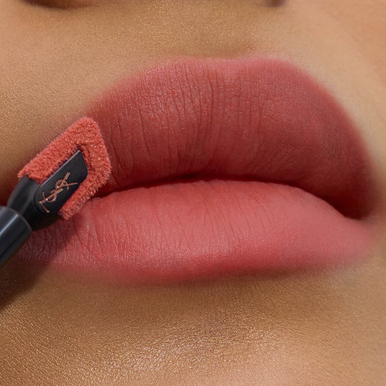 Primer plano de unos labios rosados mate y suaves siendo delineados con precisión por el aplicador de tinte labial YSL, de punta plana e inclinada.