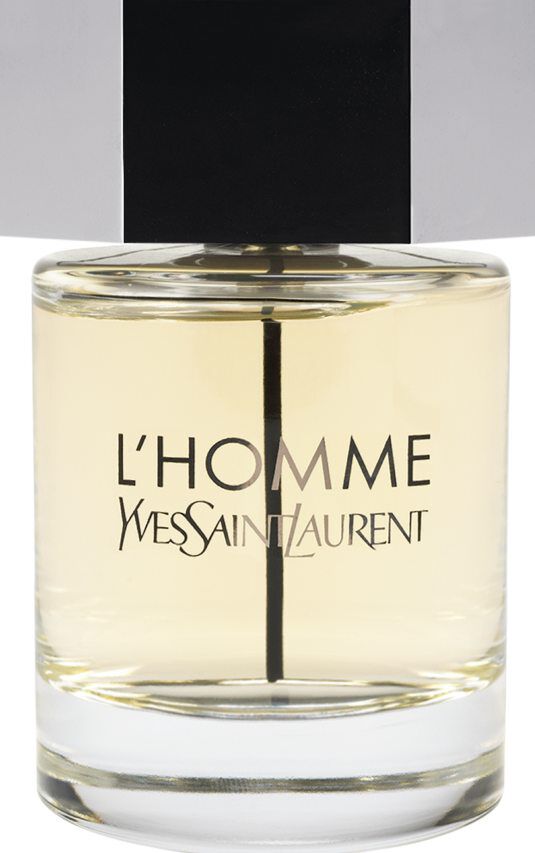 Un frasco de la fragancia Yves Saint Laurent L'Homme con cuerpo de cristal transparente, líquido ámbar claro y un gran tapón hexagonal plateado.