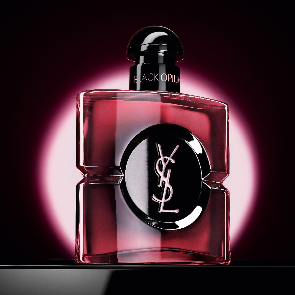El
                frasco de Black Opium Eau de Parfum Pink Glaze destacado por un brillo circular rosa
                sobre un fondo oscuro.