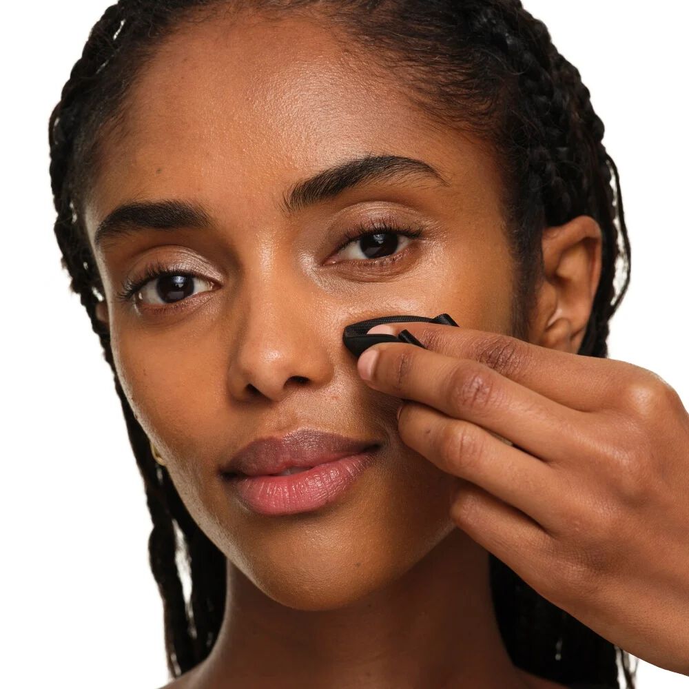 Primer plano que muestra cómo doblar la esponja de maquillaje YSL para una precisión enfocada y retoques alrededor de la nariz y los ojos.