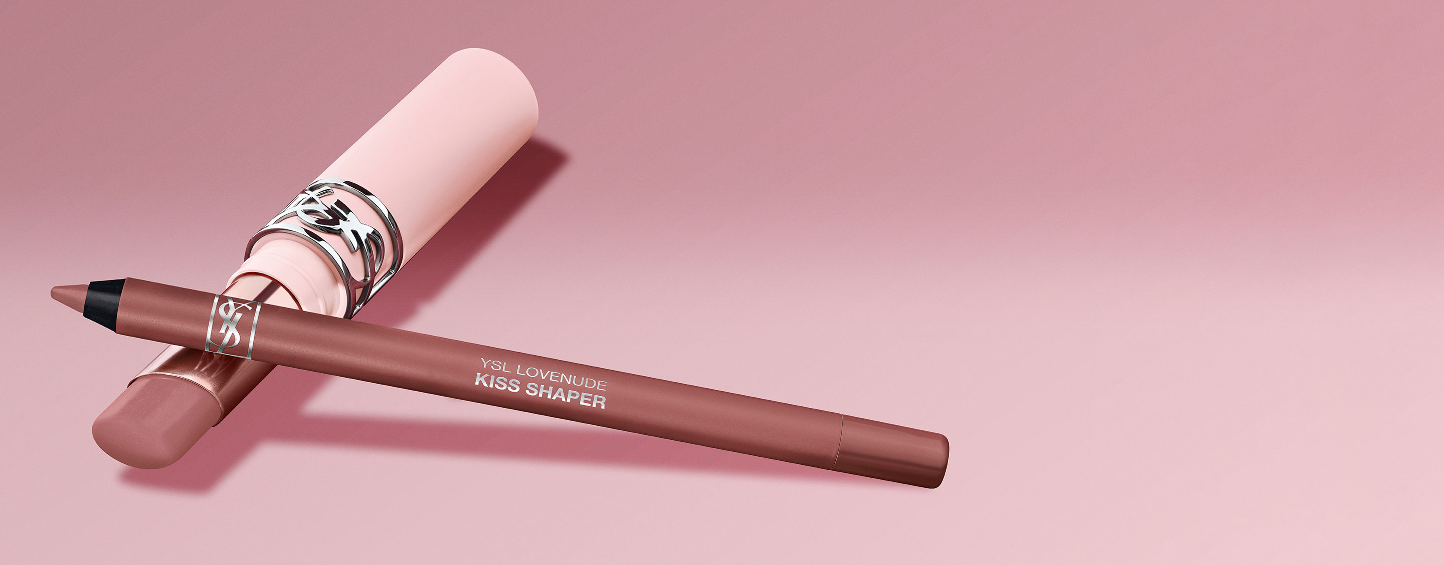 Perfilador de labios YSL Kiss Shaper y producto labial a juego sobre un fondo rosa.