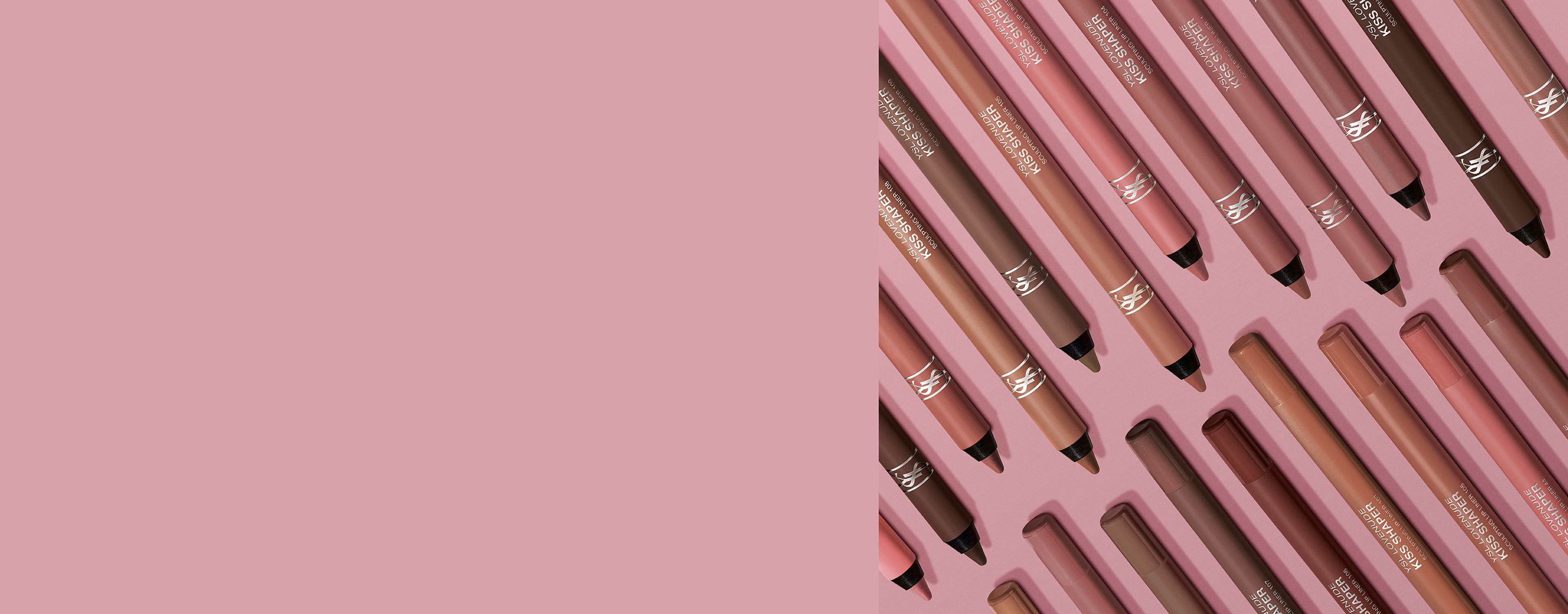 Gama de perfiladores de labios YSL Kiss Shaper en tonos nude y marrón sobre un fondo rosa.