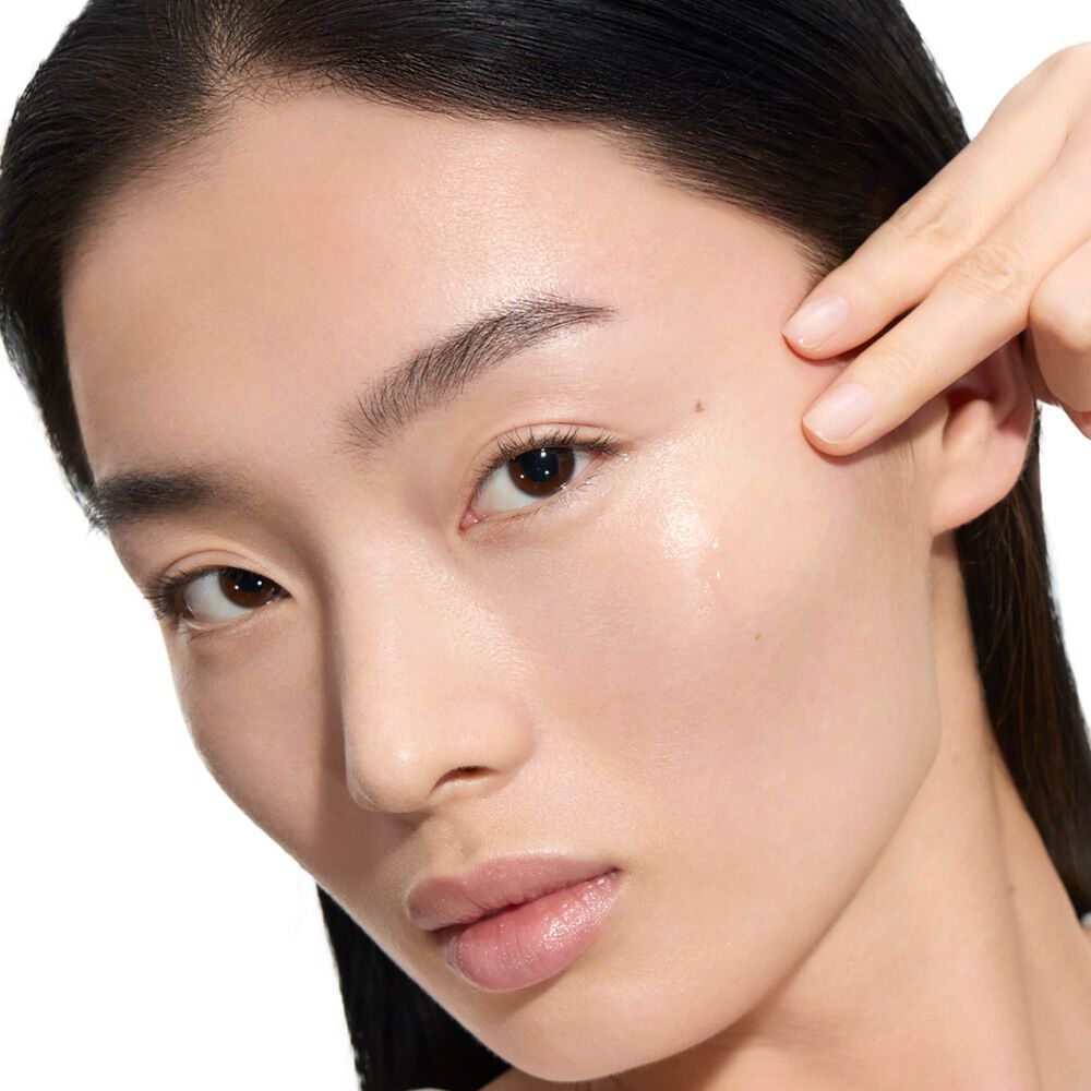 Wen, modelo de YSL Beauty, de piel clara, aplicando una gota de Pure Shots Youth Reload Serum en su mejilla.