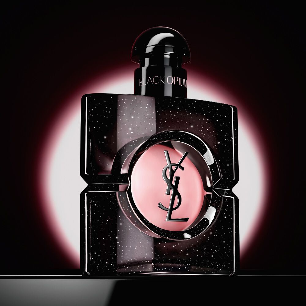 Frasco de Black Opium Eau de Parfum realzado por un resplandor circular rosa sobre un fondo oscuro.