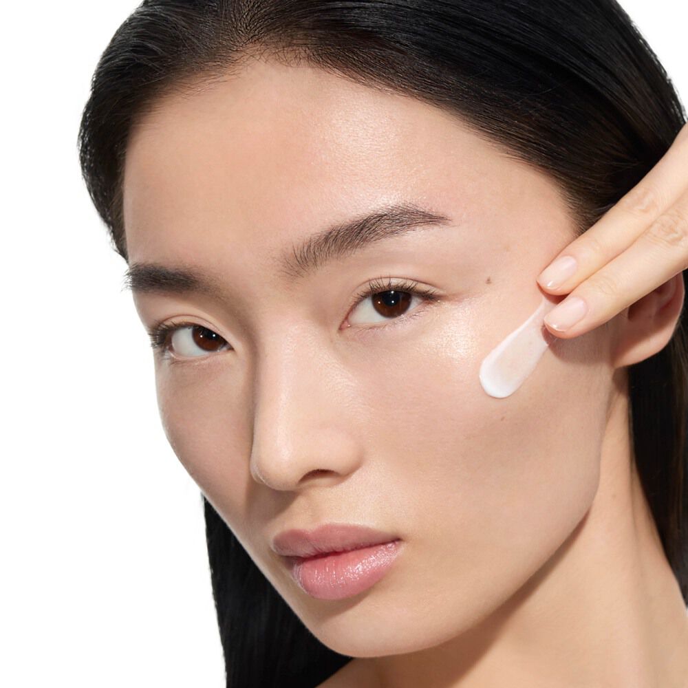 Wen, modelo de YSL Beauty, con piel clara, aplicando la crema Pure Shots Youth Reload de YSL Beauty en su mejilla.