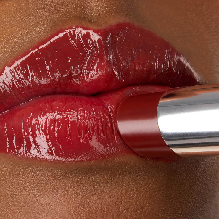 Primer plano de la barra de labios YSL LOVESHINE en el tono Berry Crush 219, aplicada sobre los labios rojos, vibrantes y brillantes de la modelo Zahara.