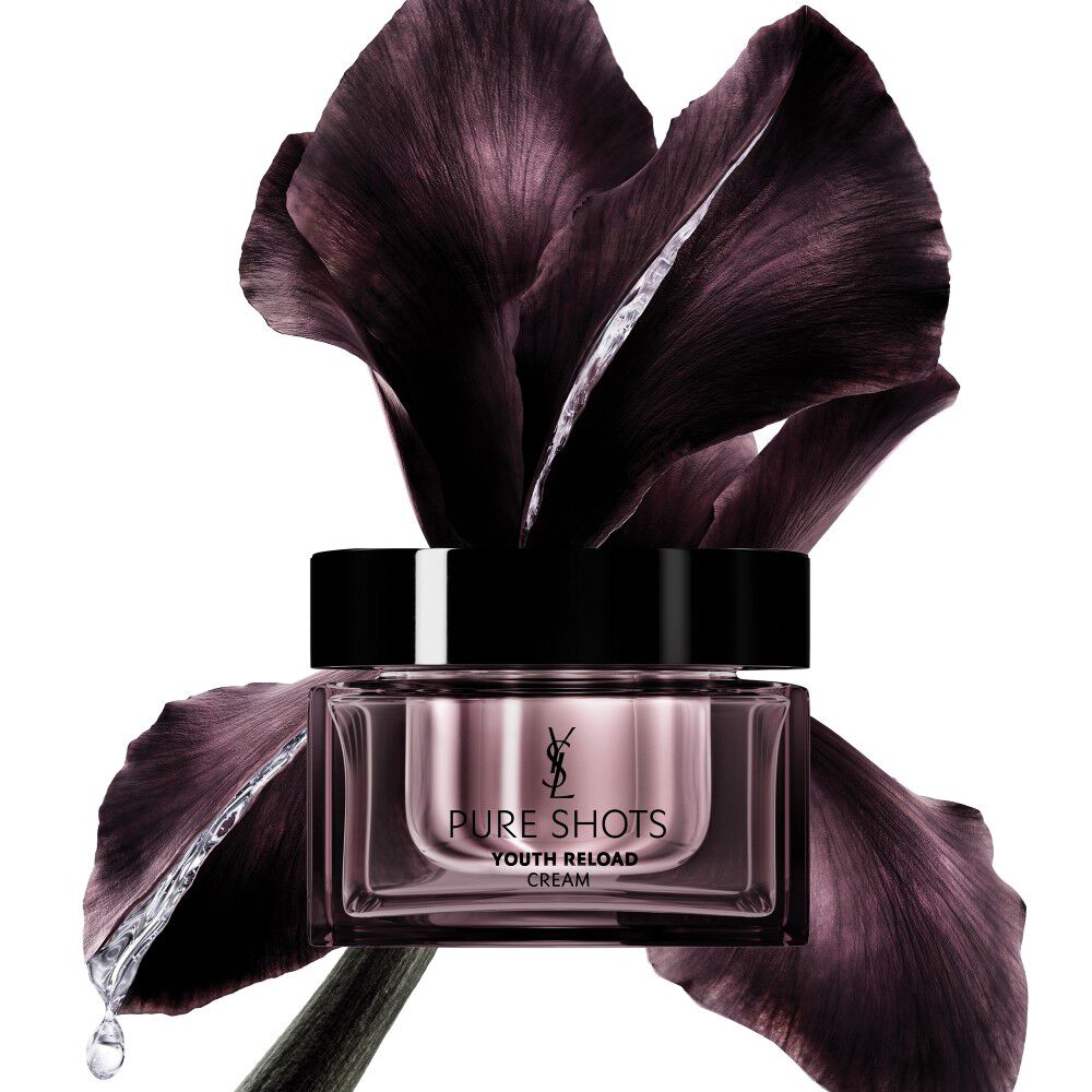 YSL Beauty Pure Shots Youth Reload, un tarro de crema elegantemente posicionado frente a una flor de iris púrpura oscuro.