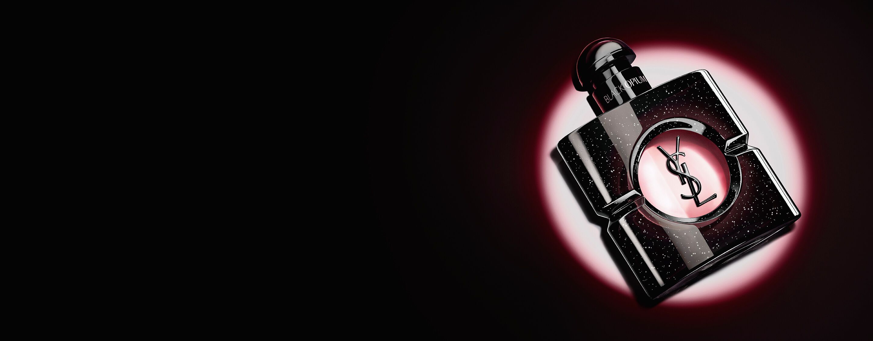 Frasco de Black Opium Eau de parfum tumbado de lado sobre una superficie oscura, envuelto en un halo de luz rosa.