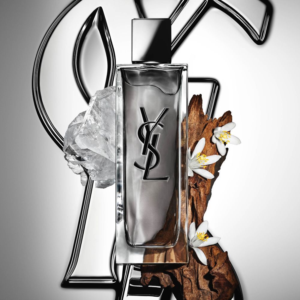 El frasco de MYSLF Eau de Toilette Intense de YSL Beauty, rodeado de flor de azahar, maderas y almizcles blancos.