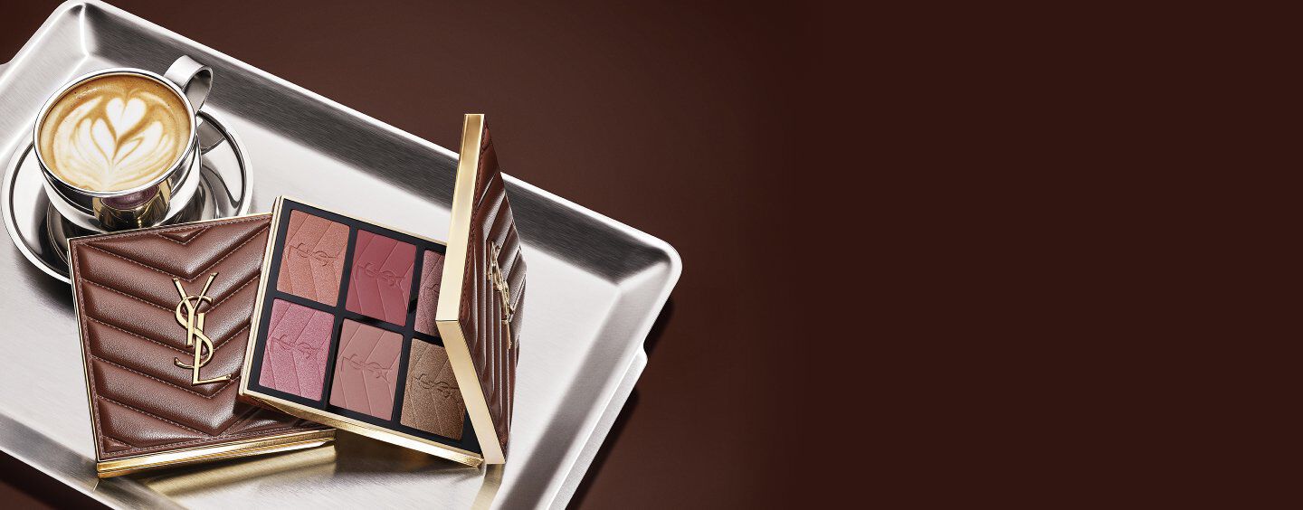Colección de maquillaje YSL Fall Drop latte con Loveshine Lip Oil, Face Palette y Make Me Blush, y una taza de café sobre una bandeja plateada