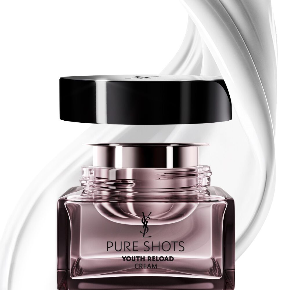 Crema YSL Beauty Pure Shots Youth Reload y su recambio sostenible, rodeados por un remolino dinámico de su textura lujosa.