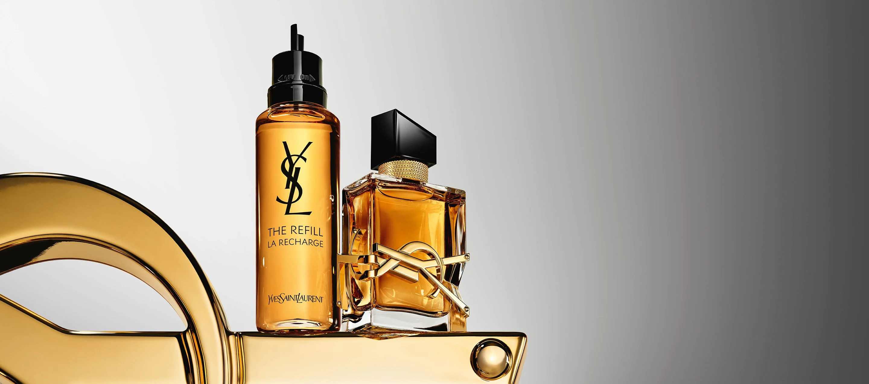 Dos frascos de perfume Yves Saint Laurent Libre, uno de recarga, en un expositor dorado.