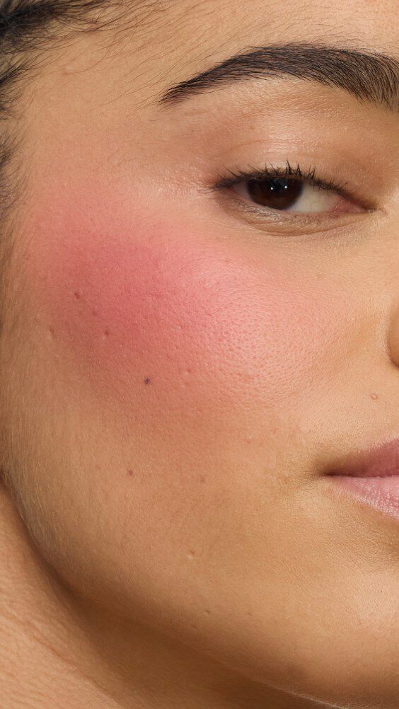 Primer plano del pómulo de una modelo con la rutina Make Me Blush: Polvo #54 Berry Bang superpuesto con Crema #44 Nude Lavallière para un rosa vibrante y personalizado.